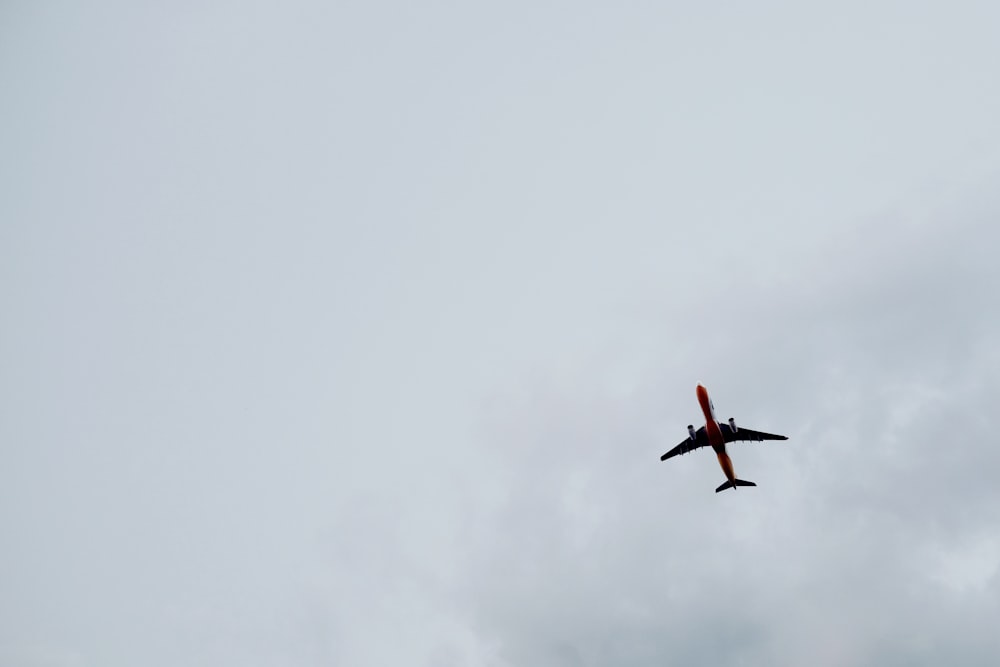 fotografia ad angolo basso del volo dell'aereo sotto il cielo nuvoloso