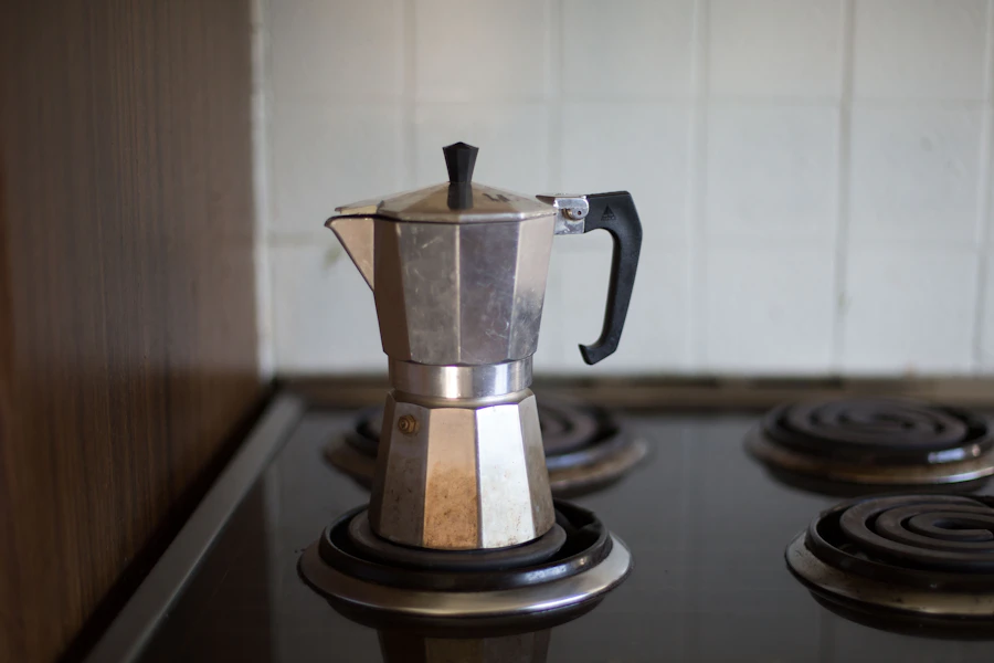 Gray Moka pot on an electric coil stove, selective focus