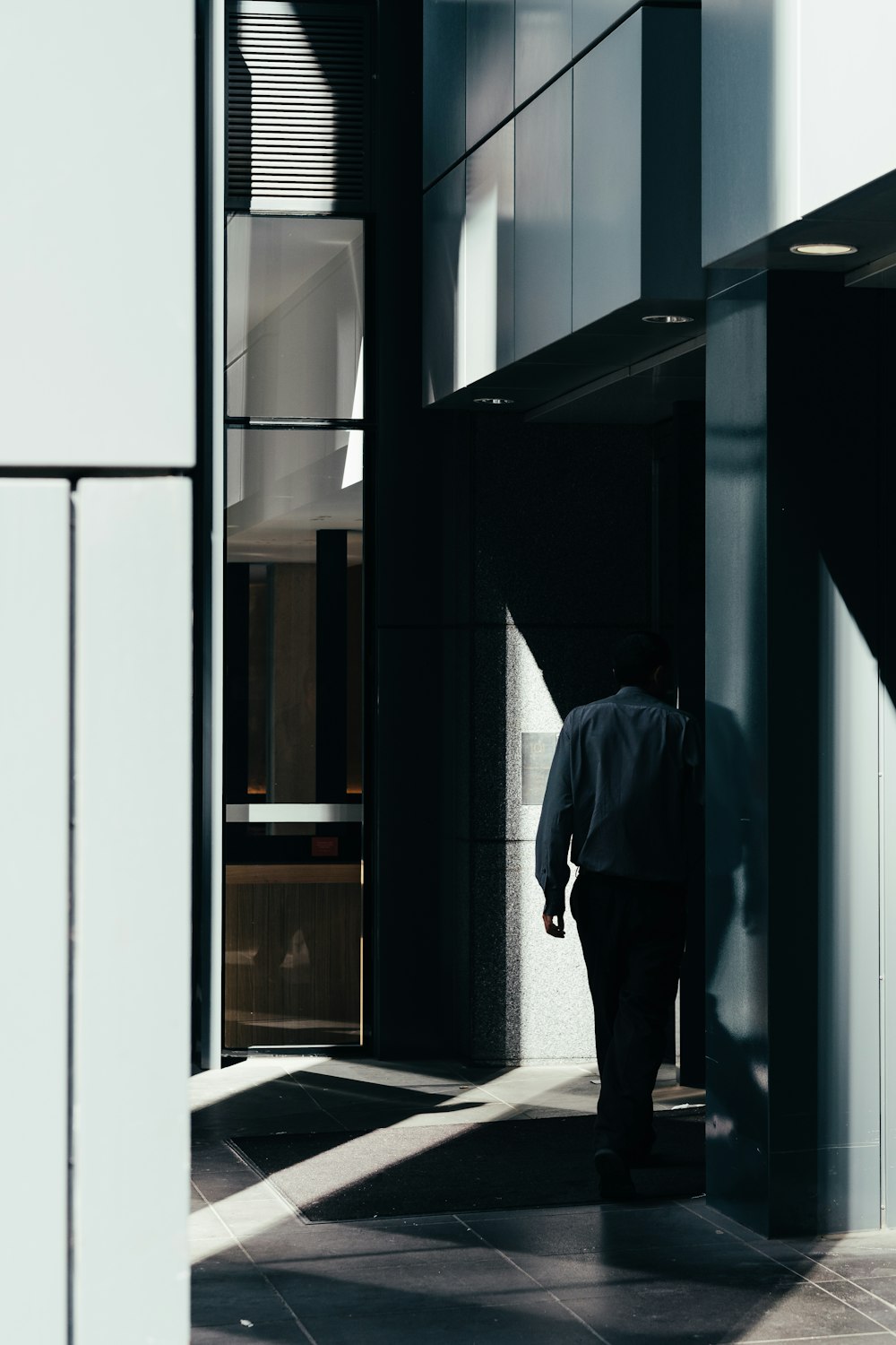 man walking on gray tiled pathway inside building