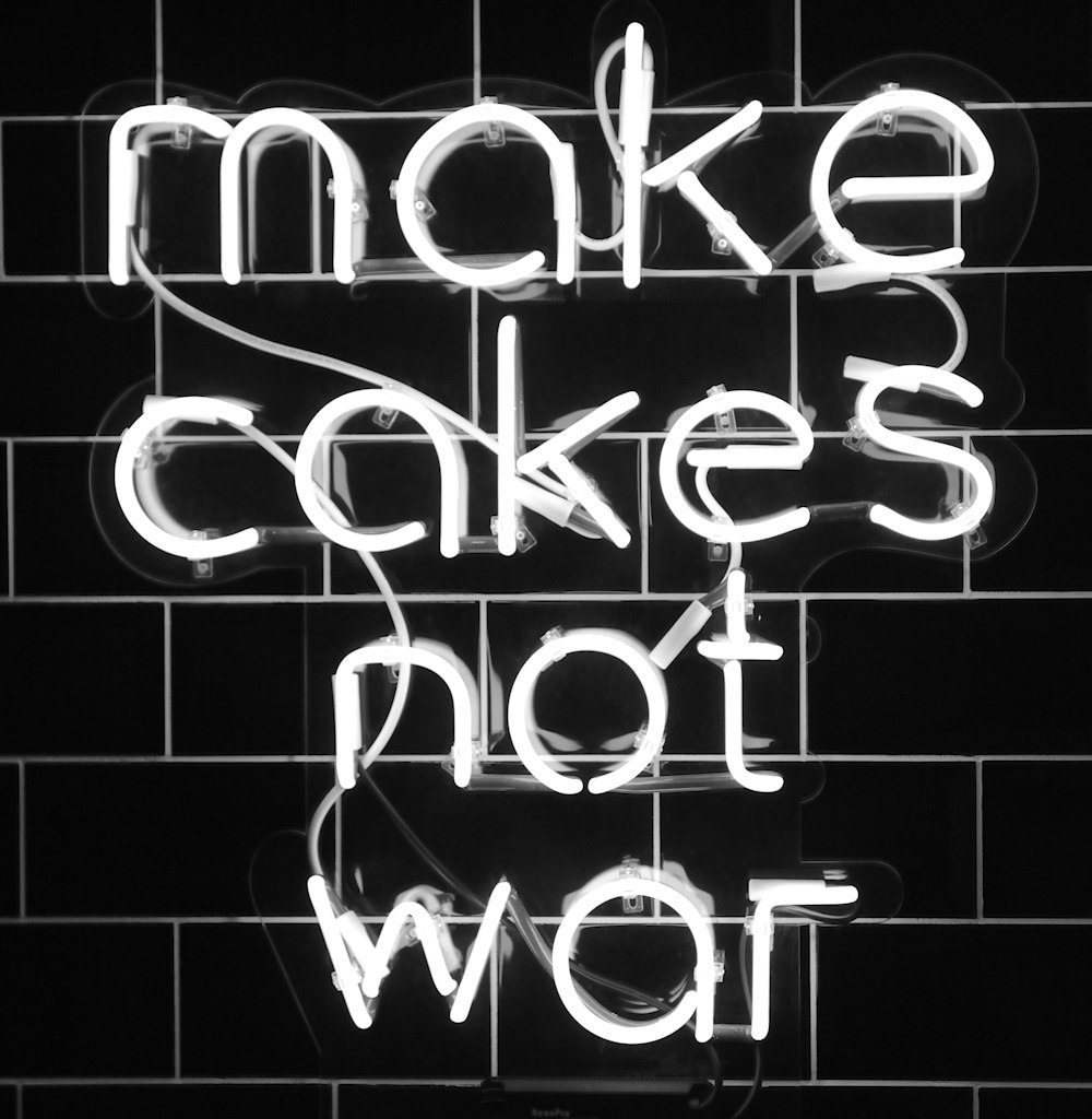 white make cakes not war neon sign