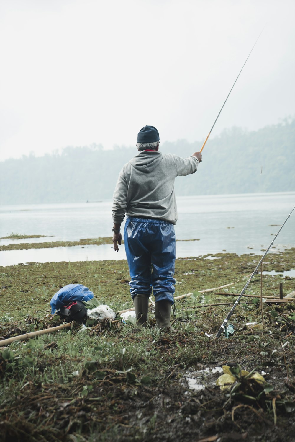 man standing on shore holding fishing rod
