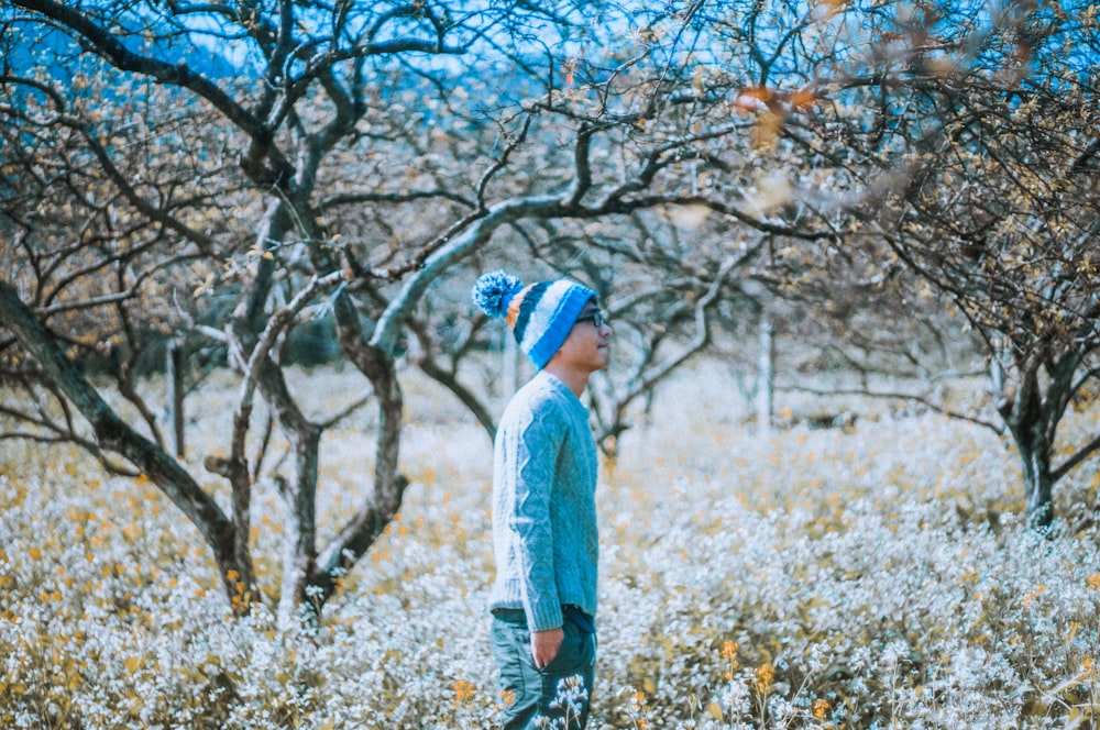 selective focus photography of man walking on bed of flowers