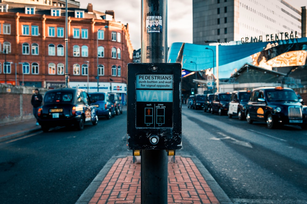 Selektive Fokusfotografie von Fußgängern, die tagsüber einen Knopf zwischen den Straßen steuern