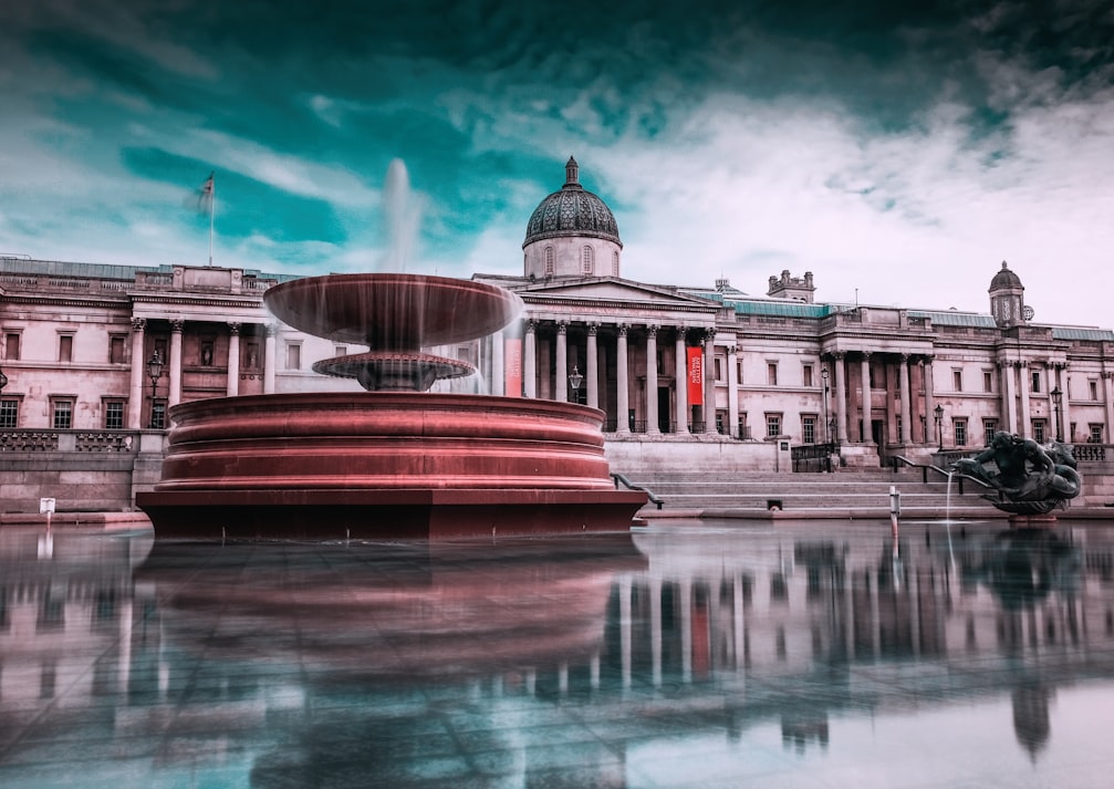 a fountain in trafalgar square with the national gallery in the background
