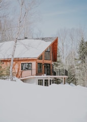 beige and white wooden house surrounded by snowy field during daytime