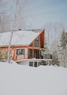 beige and white wooden house surrounded by snowy field during daytime