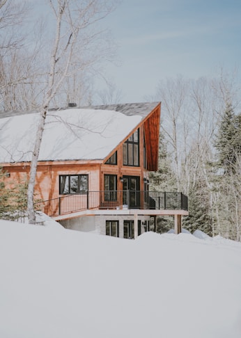 beige and white wooden house surrounded by snowy field during daytime