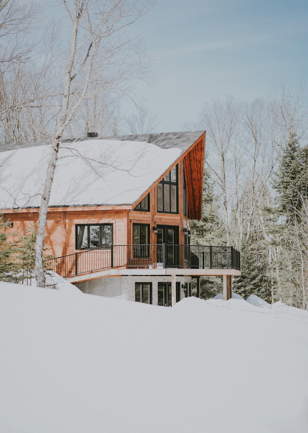 昼間は雪原に囲まれたベージュと白の木造住宅