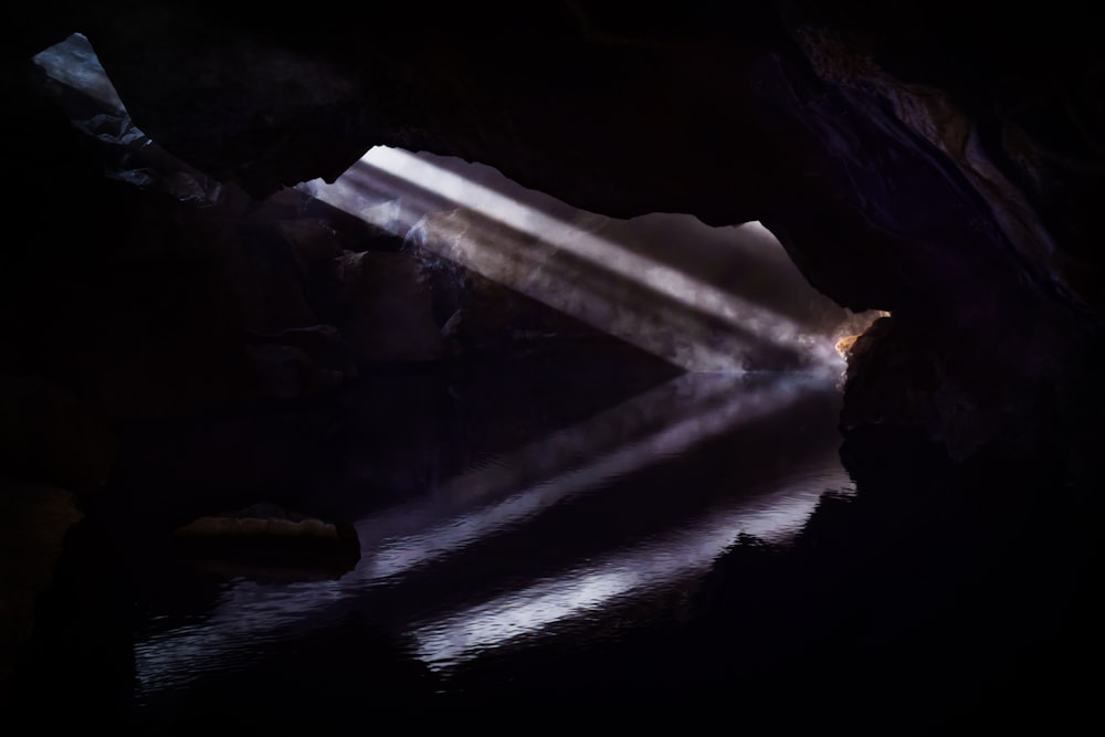 a light shines through a cave door into a body of water