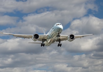 airliner flying under white clouds during daytime