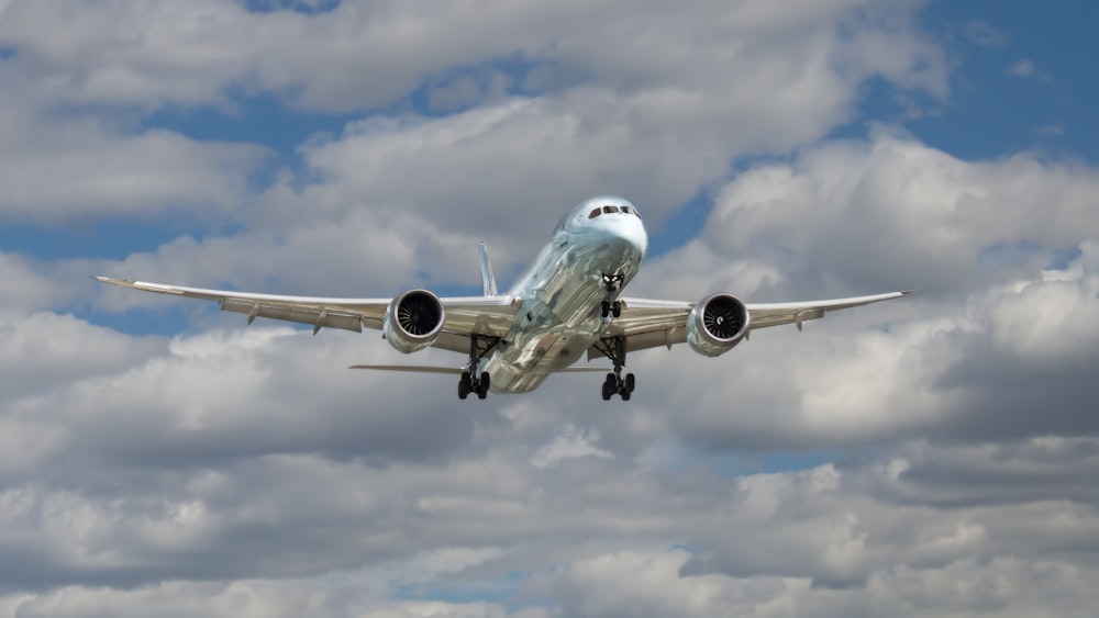 airliner flying under white clouds during daytime