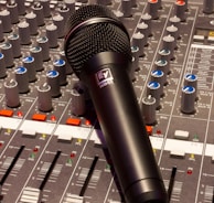 black wireless microphone on grey and multicolored audio mixer