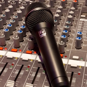 black wireless microphone on grey and multicolored audio mixer