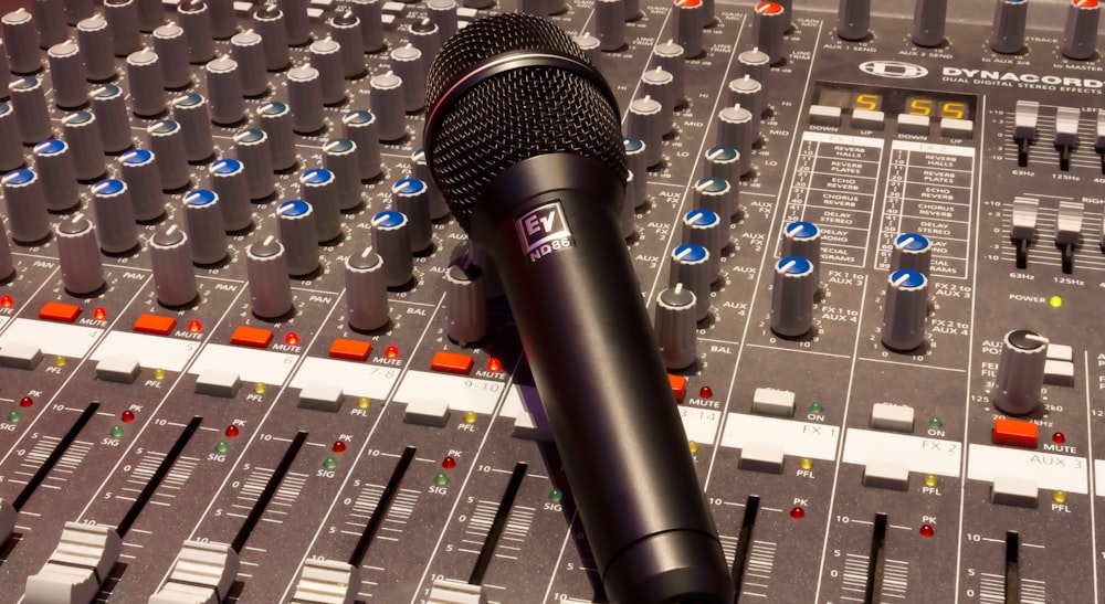 black wireless microphone on grey and multicolored audio mixer