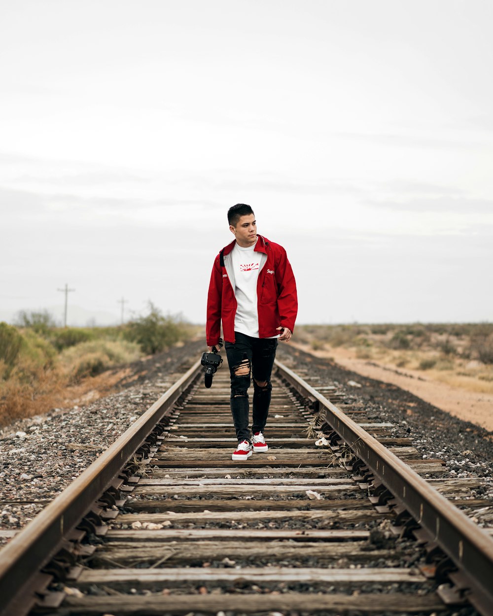 man wearing jacket waking on train rail