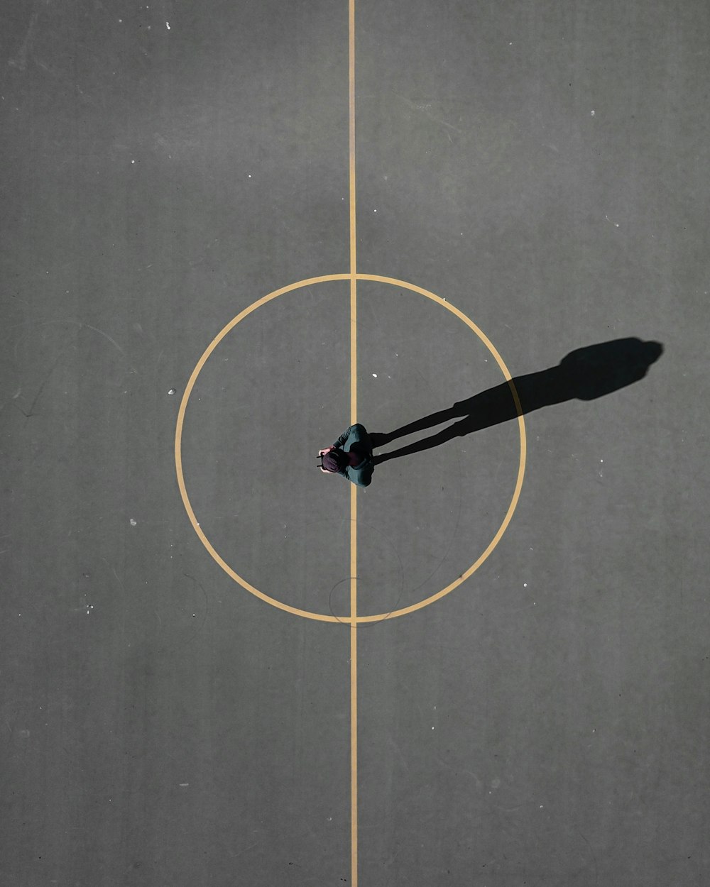 man stainding on black concrete floor casting shadow