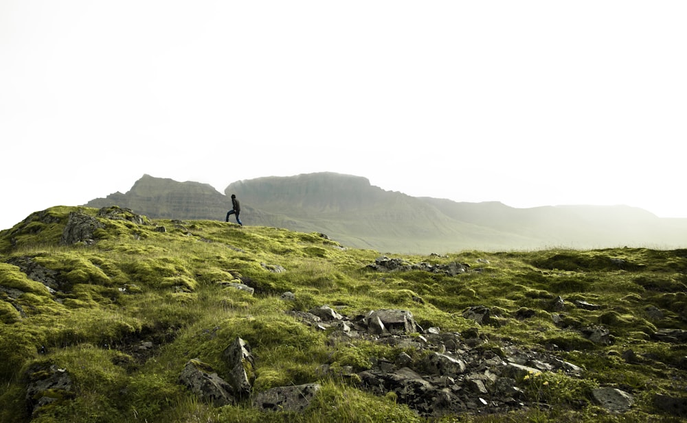 person standing on green grass covered mountain during daytime