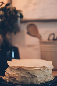 A stack of crepas with layers of fruit and syrup, served on a rustic wooden table inside Mentafiú Café.