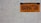 An orange and black Manhattan license plate is mounted on a white tiled wall. The plate features the words 'New York' at the top, 'Manhattan' in the middle, and 'Empire State' at the bottom.