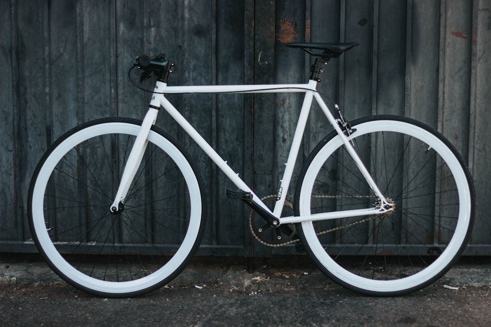 Bicicleta de carretera blanca junto al panel de acero gris