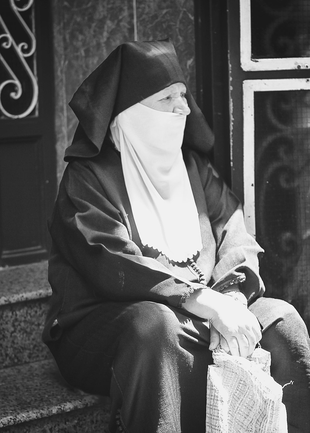 woman in overall suit sitting on staircase in grayscale photography