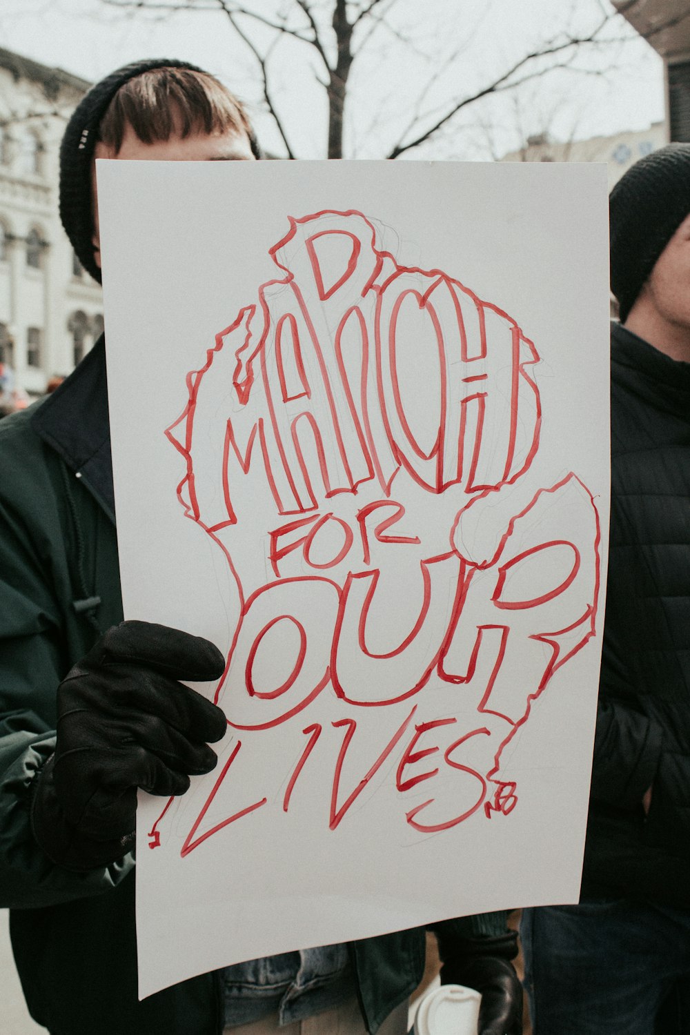 person holding board with march for our lives text