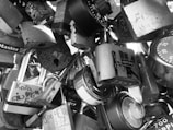 A collection of different padlocks and combination locks clustered together, with some locks displaying inscriptions or engravings. The locks vary in shape and design, creating an intricate pattern resembling a makeshift sculpture.