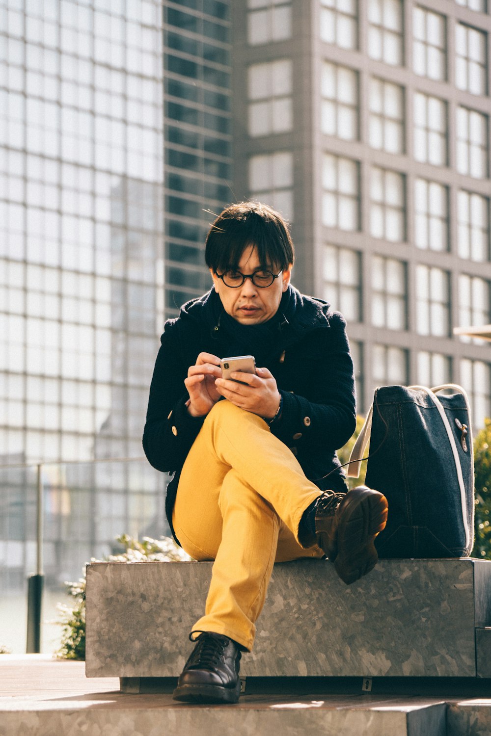 homem usando smartphone sentado em banco de concreto