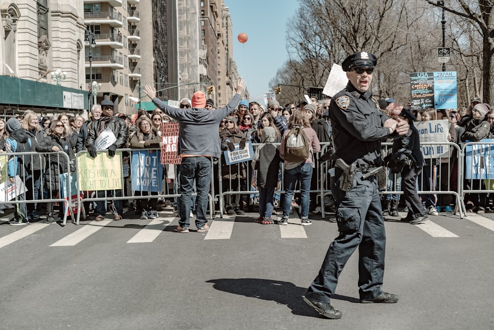 police man standing on road near people watching