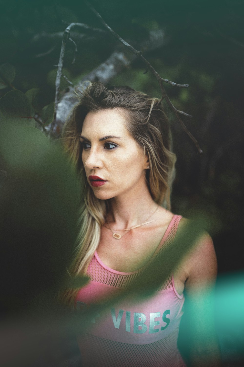 shallow focus photo of woman wearing tank top posing below tree