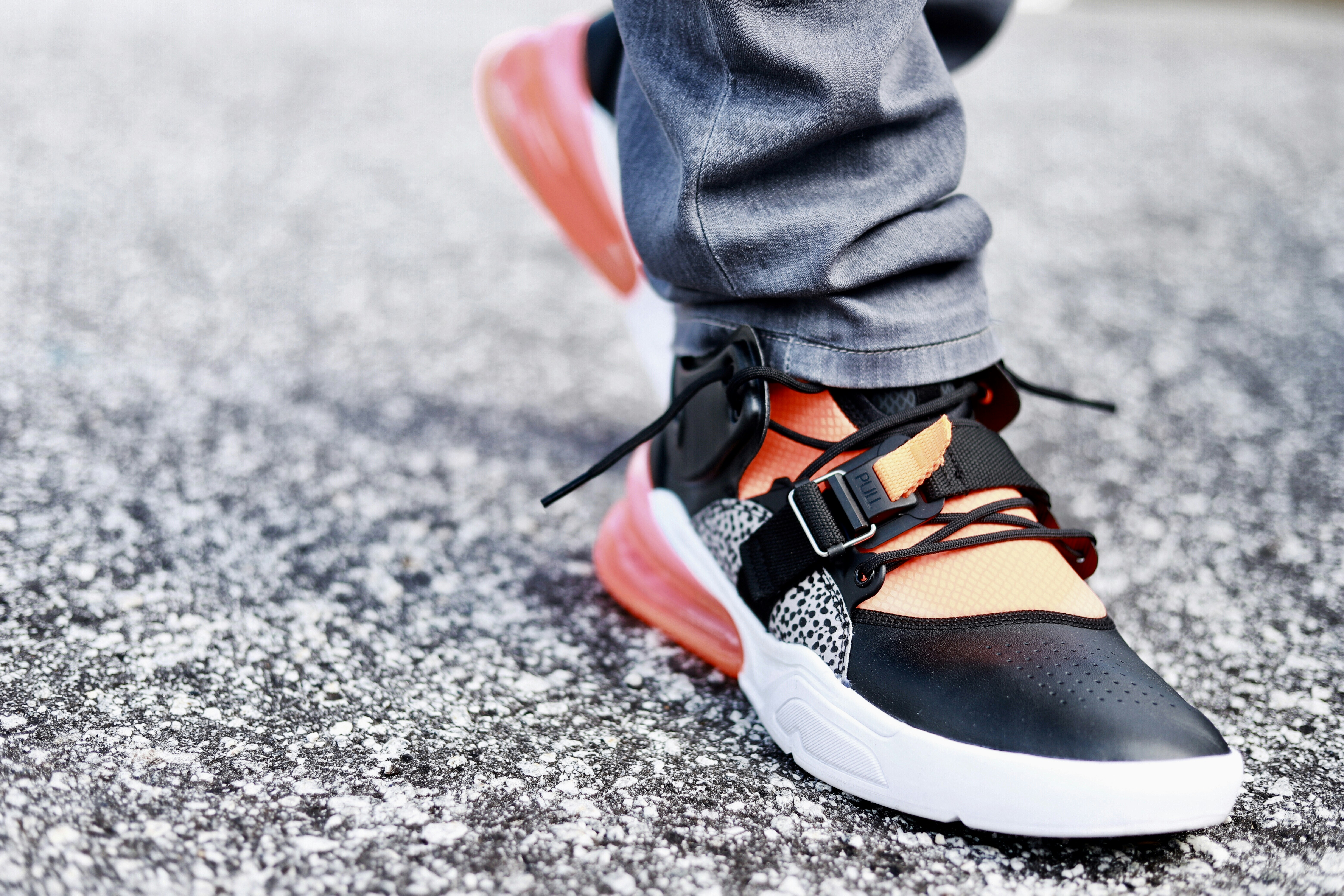 Persona que viste jeans de mezclilla azules y zapatos deportivos negros, blancos y naranjas