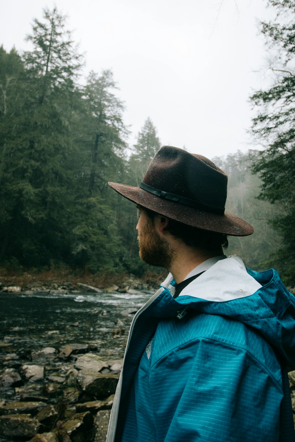 Mann mit schwarzem Hut steht in der Nähe des Flusses