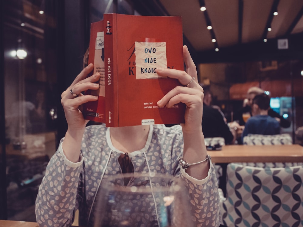 woman sitting in front of table reading book