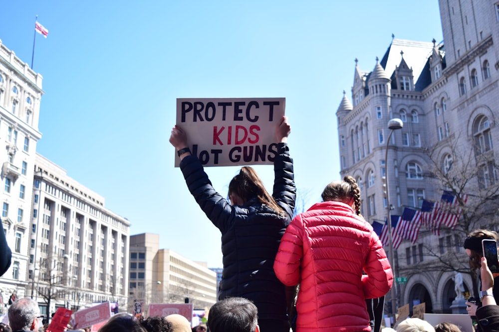 woman in black jacket holding signage panel