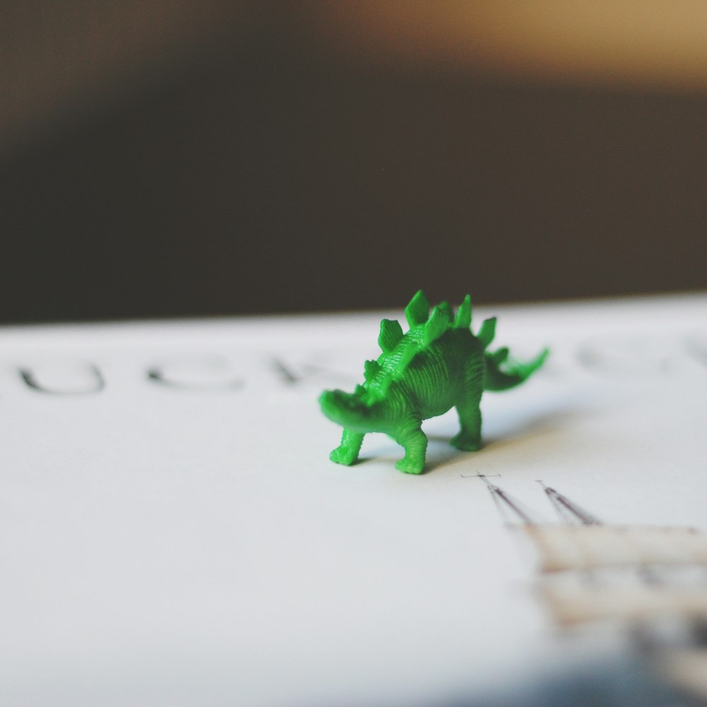 selective focus photography of green dinosaur toy