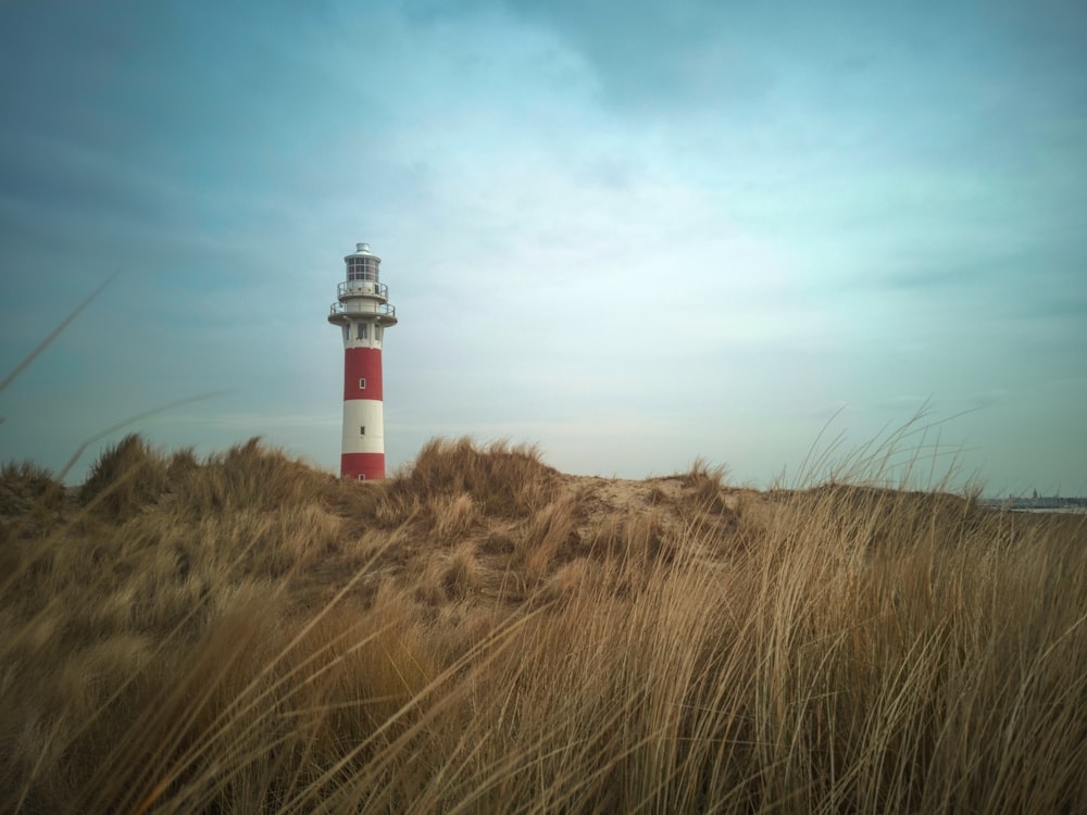 red and white lighthouse near grass field during daytime