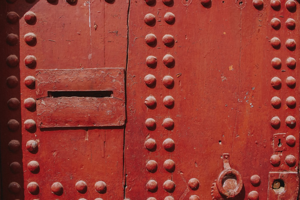 a close up of a red door with rivets
