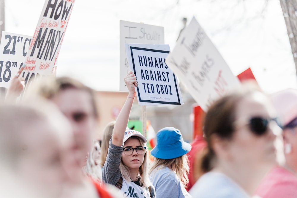 mujer sosteniendo el cartel de Humans Against Ted Cruz durante el día