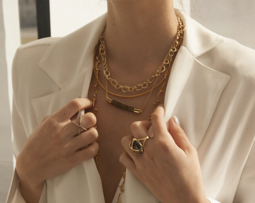 Close-up of layered gold jewelry and textured fabrics capturing a chic yet effortless vibe