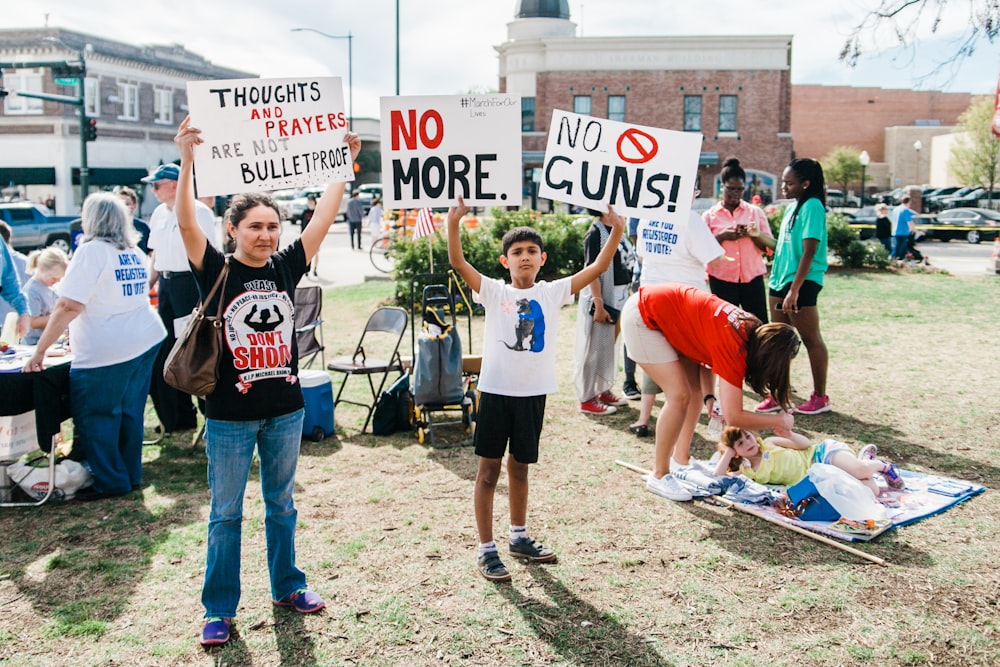 people holding signage on green grass field