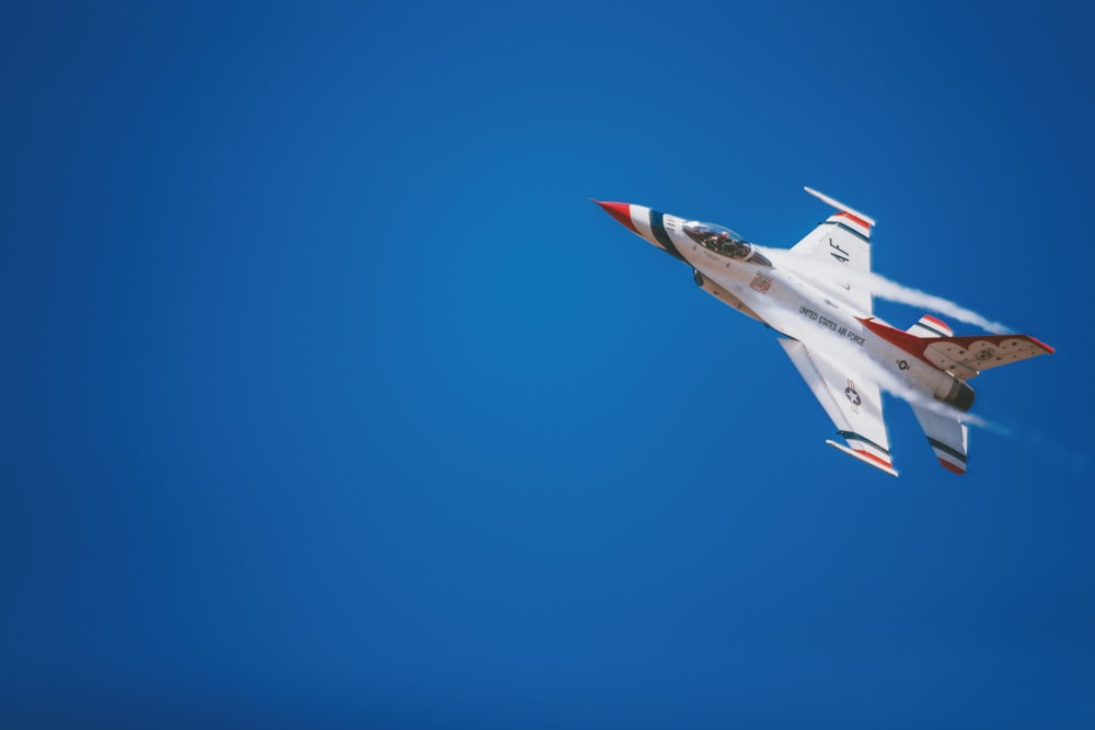 white and red jet plane hovering on sky at daytime