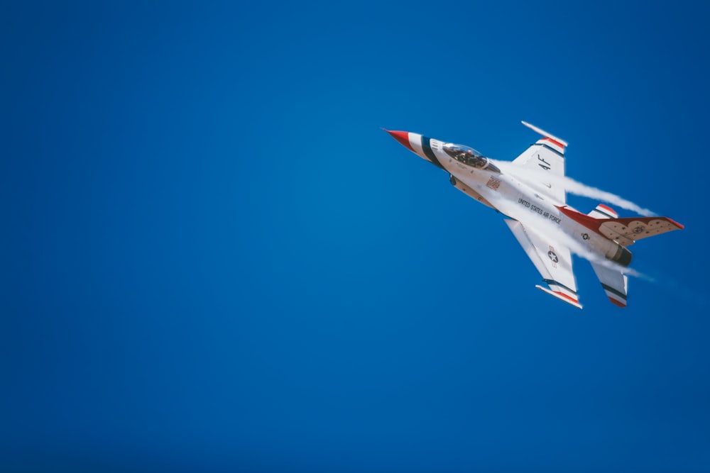 white and red jet plane hovering on sky at daytime