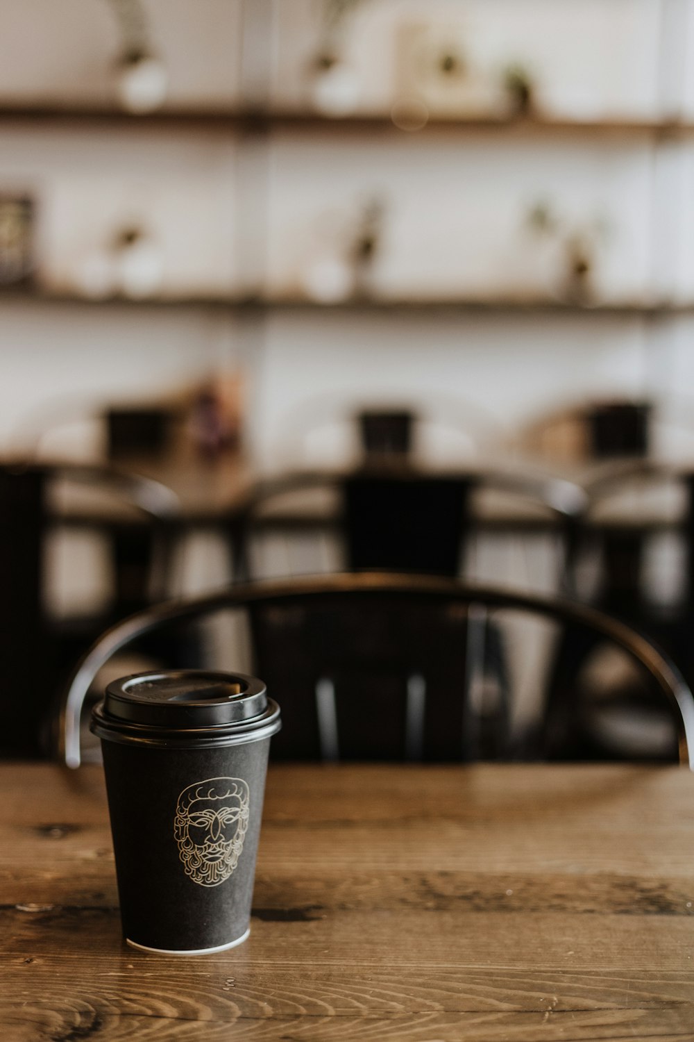 木製のテーブルに黒い使い捨てコーヒーカップ