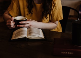 woman holding mug in front of book