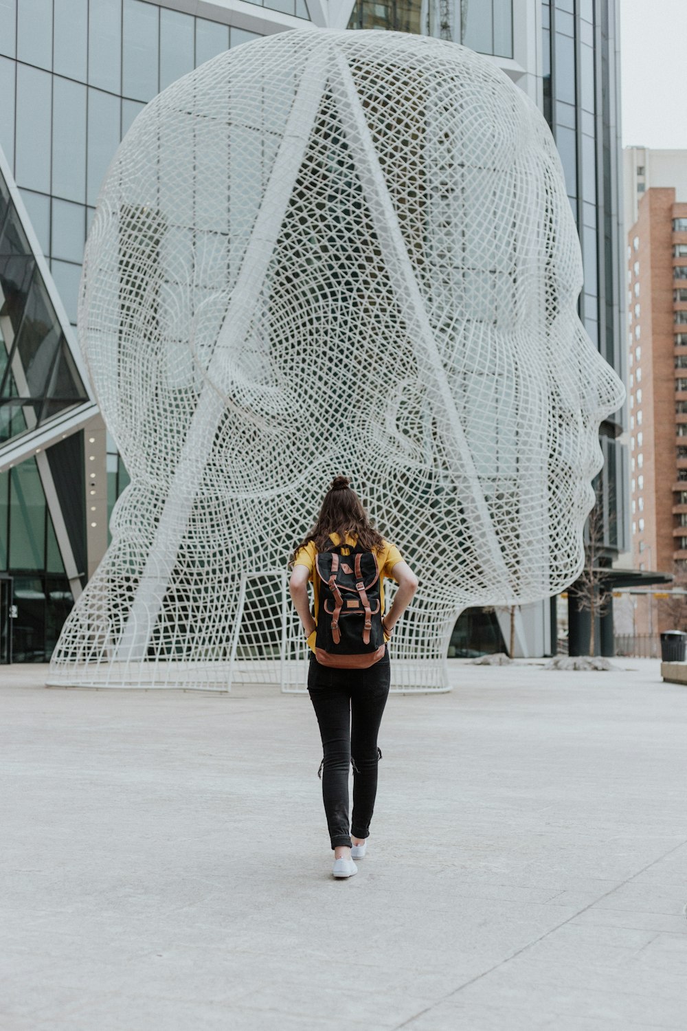 person walking toward face statue