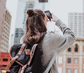 woman taking photo of high-rise building beside road