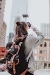 woman taking photo of high-rise building beside road