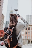 woman taking photo of high-rise building beside road