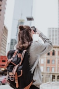 woman taking photo of high-rise building beside road