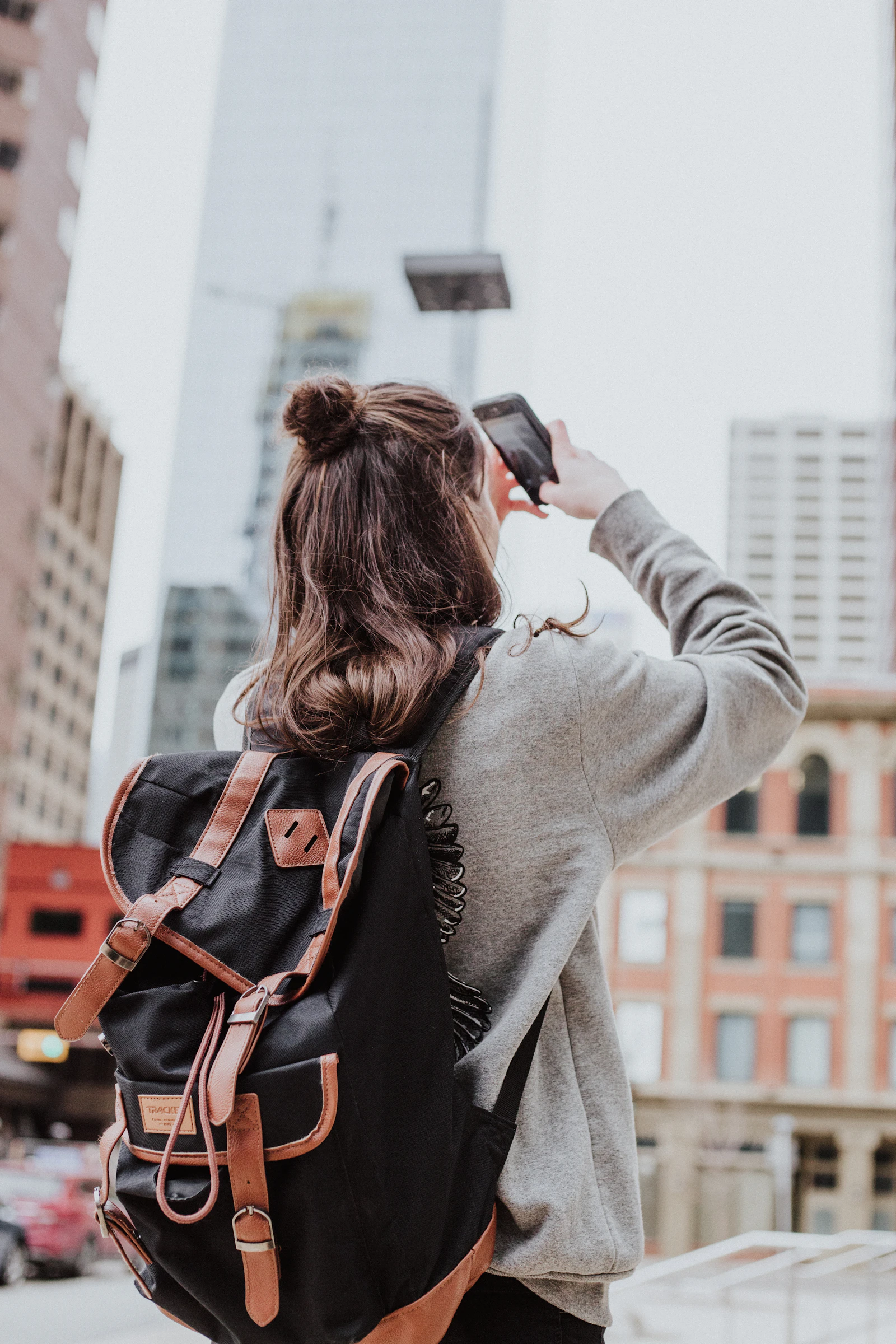 Mujer tomando una foto de un edificio al lado de la carretera